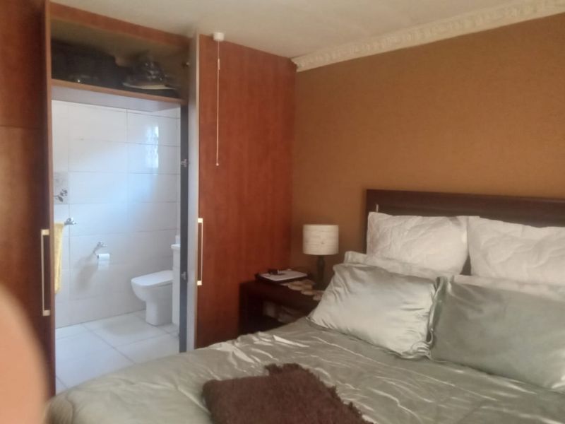 Bedroom featuring built-in wooden cabinetry and an adjoining en-suite bathroom with tiled finishes.