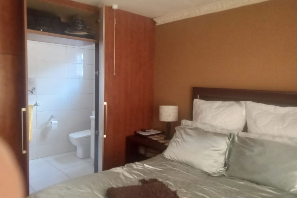 Bedroom featuring built-in wooden cabinetry and an adjoining en-suite bathroom with tiled finishes.