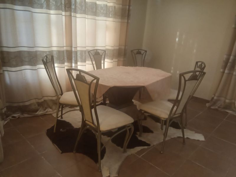 A dining area featuring tiled flooring and neutral curtains, providing a functional space for meals.
