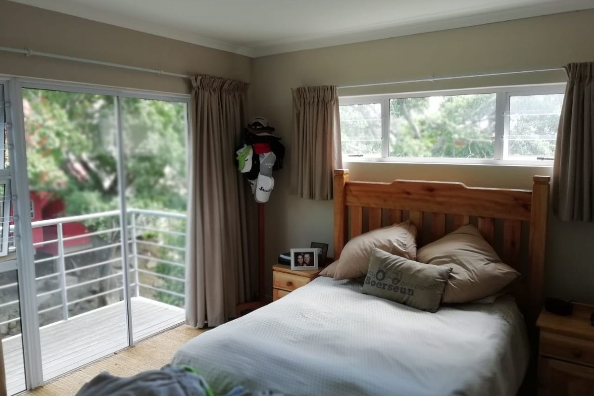 A bedroom featuring a sliding glass door leading to a balcony and horizontal windows, providing natural light and outdoor access.