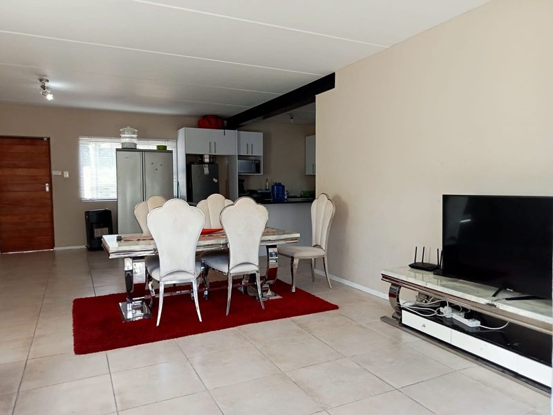 Open-plan living and dining area featuring tiled flooring, recessed lighting, and a functional kitchen with built-in cabinetry and a breakfast counter.