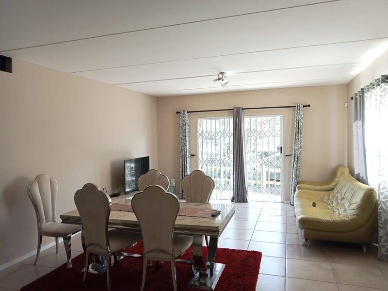 Open plan living and dining area featuring tiled flooring and a sliding glass door with security gate leading to the exterior.
