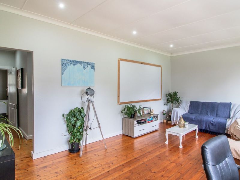 A spacious living room featuring warm timber flooring, recessed downlighting, and neutral wall finishes, providing a comfortable and versatile living area.