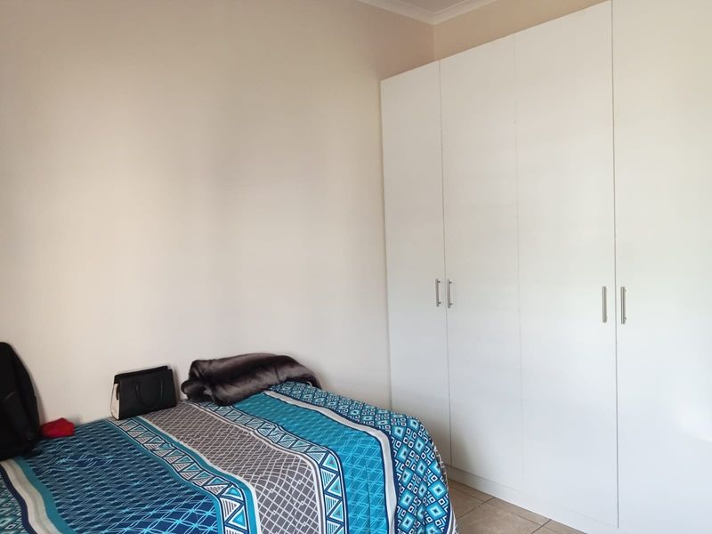 A bedroom featuring neutral walls, tiled flooring, and ample built-in cupboard storage.