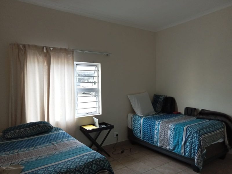 A functional bedroom featuring tiled flooring and a louvered window, providing a neutral space ready for personalization.