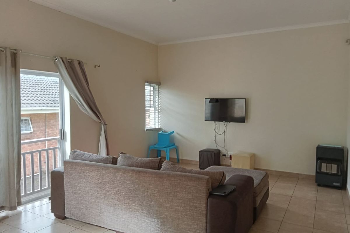 A living room featuring tiled flooring, a sliding glass door leading to a balcony, and neutral wall finishes.