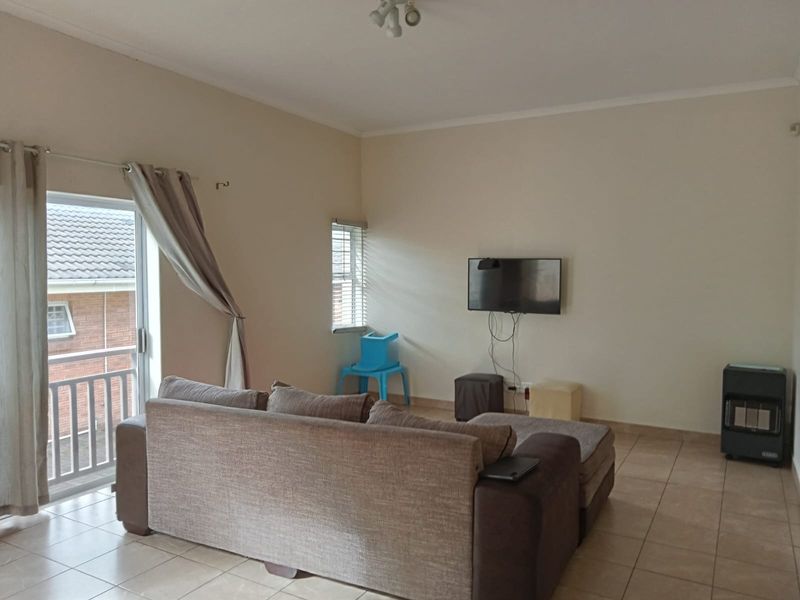 A living room featuring tiled flooring, a sliding glass door leading to a balcony, and neutral wall finishes.