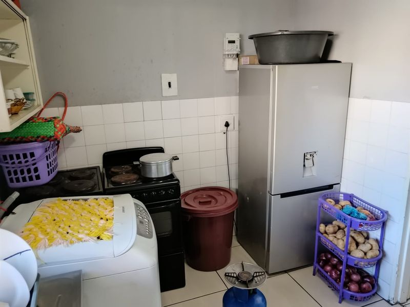 A compact kitchen area featuring a tiled splashback, built-in stove, and oven, currently utilized for laundry and storage.