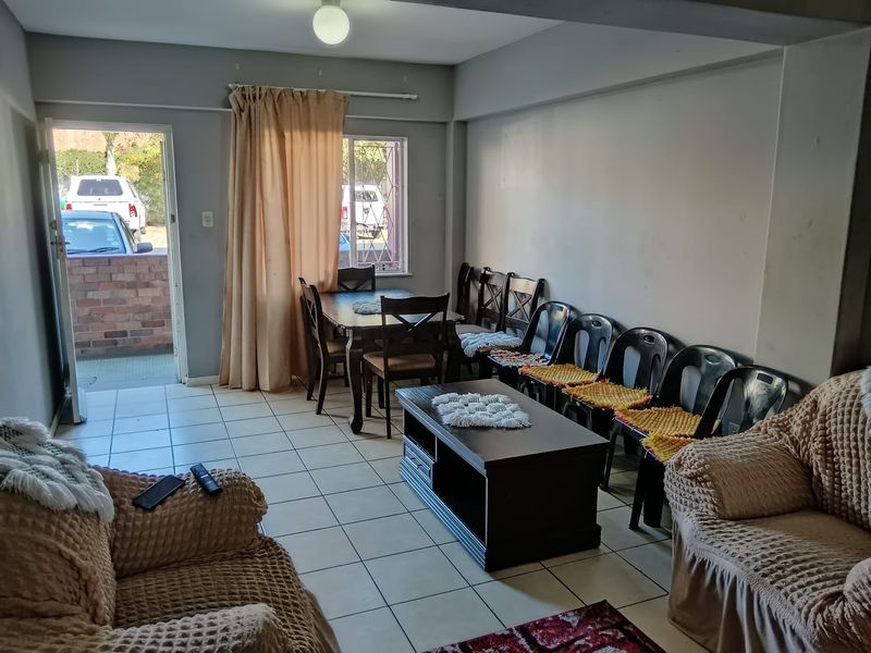 Open plan living and dining area featuring ceramic floor tiles, natural light from windows, and direct access to the exterior.