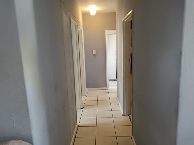 A functional hallway featuring tiled flooring and neutral wall paint, providing access to multiple rooms within the apartment.