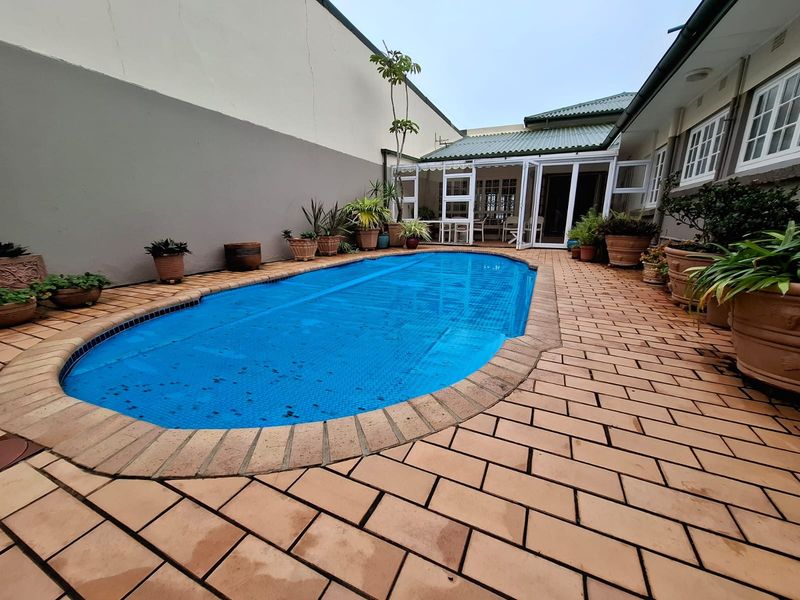 Outdoor pool area featuring brick paving, a covered swimming pool, and direct access to the home through glass french doors.