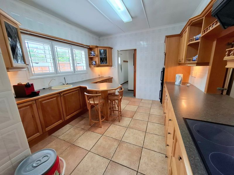 A functional kitchen featuring traditional wooden cabinetry, laminate countertops, ceramic tile flooring, and wall tiling, offering a classic layout with ample storage space.