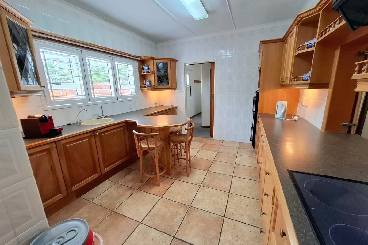 A functional kitchen featuring traditional wooden cabinetry, laminate countertops, ceramic tile flooring, and wall tiling, offering a classic layout with ample storage space.