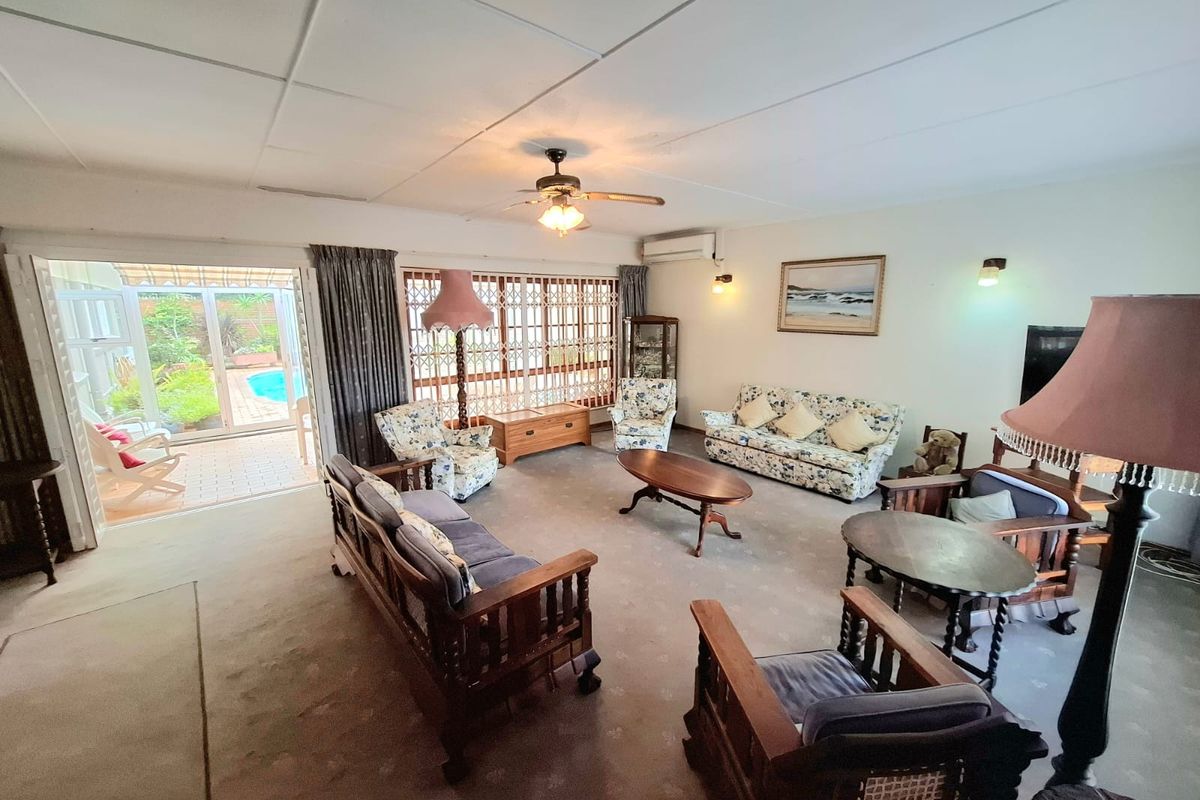 Spacious living room featuring a ceiling fan, split system air conditioning, and large sliding glass doors providing direct access to the outdoor patio and pool area.