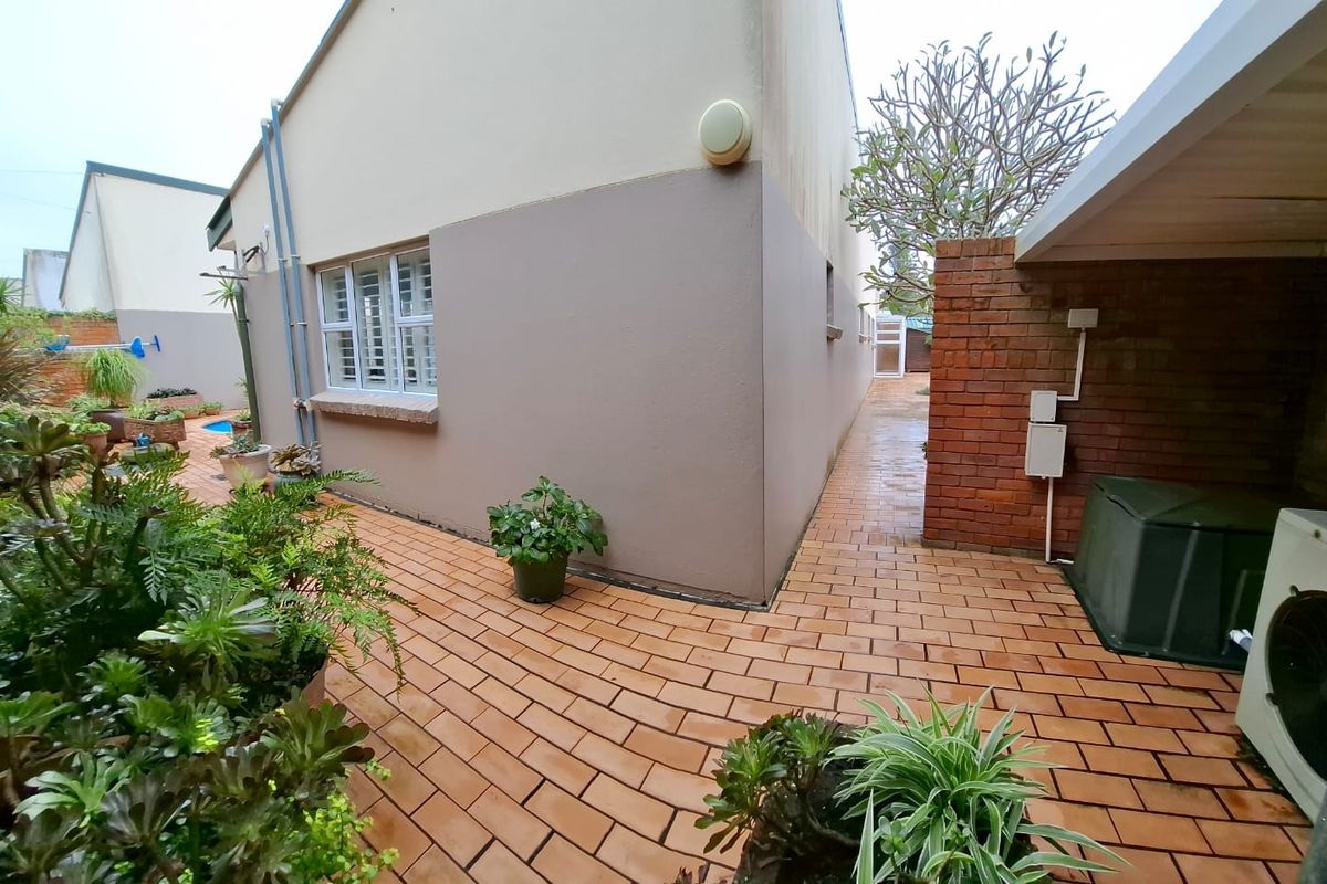 A side view of the property featuring brick paved pathways, an exposed brick wall, and a covered outdoor area.
