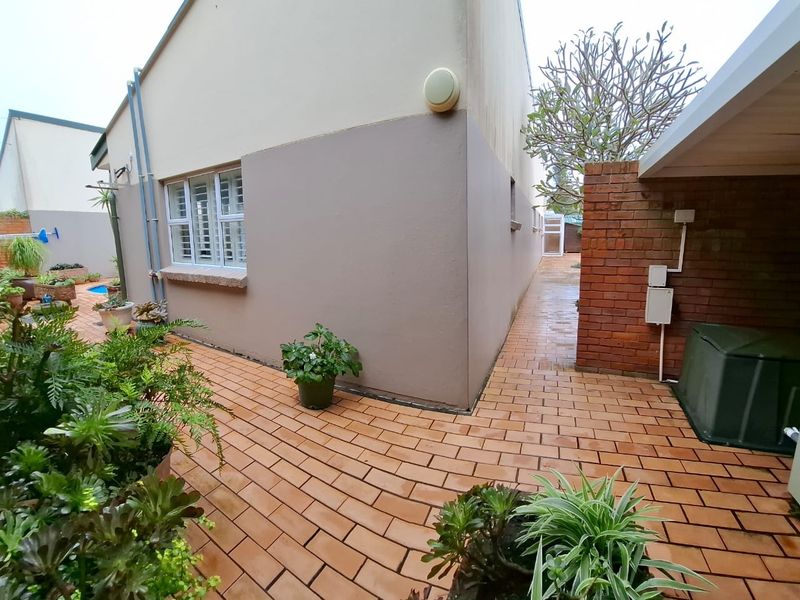 A side view of the property featuring brick paved pathways, an exposed brick wall, and a covered outdoor area.
