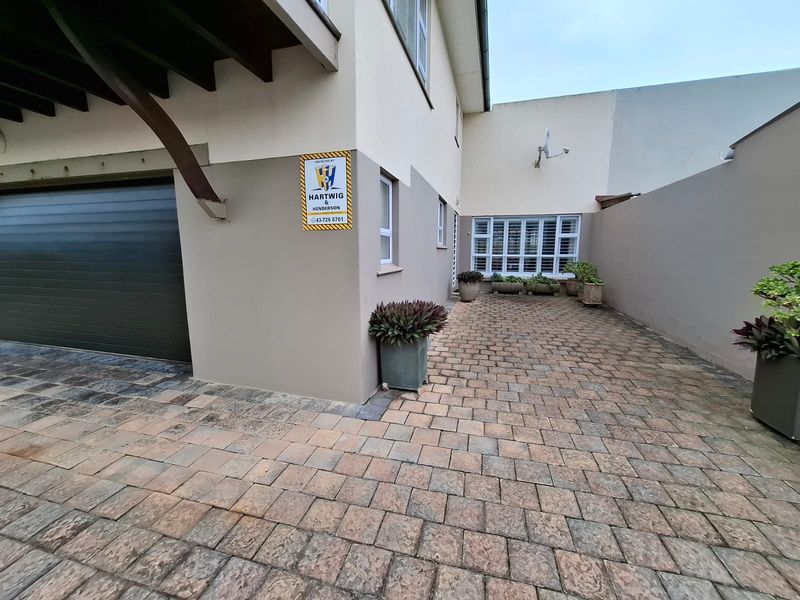 A paved front courtyard area featuring a garage entrance and secure window shutters.