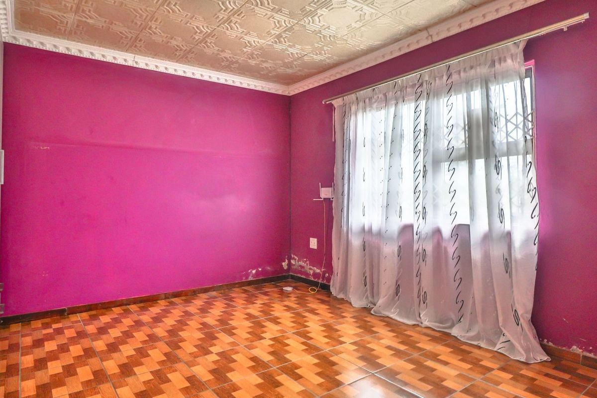 An empty bedroom featuring tiled flooring, built-in cupboards, and decorative ceiling tiles, requiring cosmetic updates to the wall finishes.