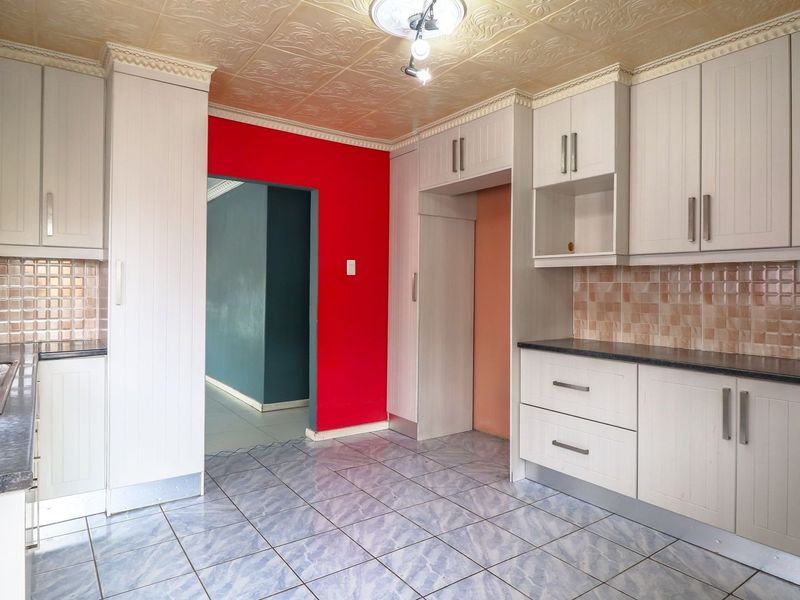 A functional kitchen featuring built-in cabinetry, laminate countertops, a double bowl sink, and decorative ceiling tiles, offering a blank canvas for modern updates.