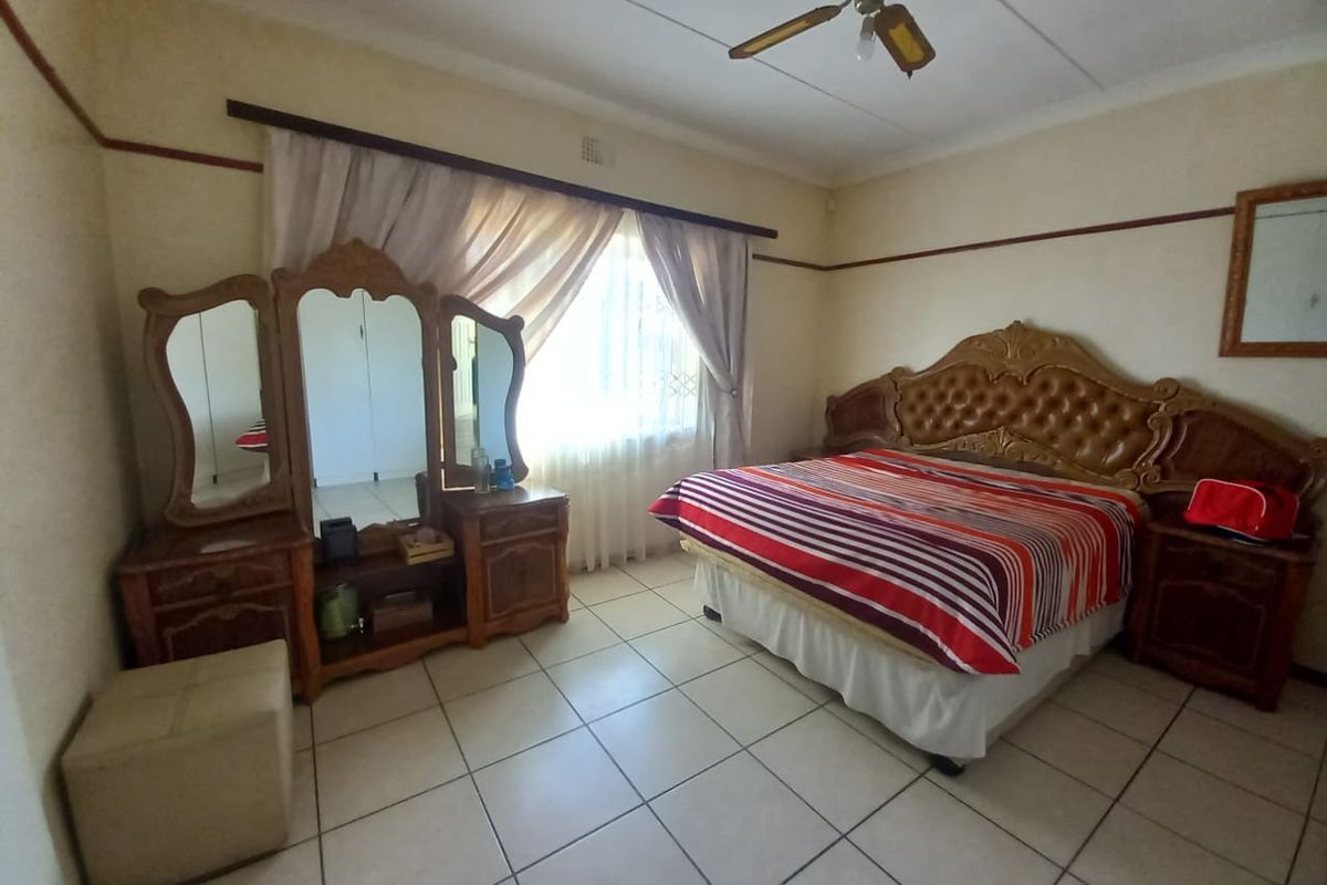 Spacious bedroom featuring tiled flooring, a ceiling fan, and built-in storage, offering a functional layout with natural light from the window.