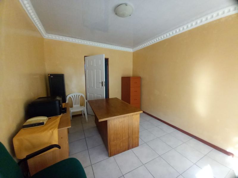 A functional office space featuring tiled flooring and decorative ceiling cornicing, suitable for a home workspace or study area.