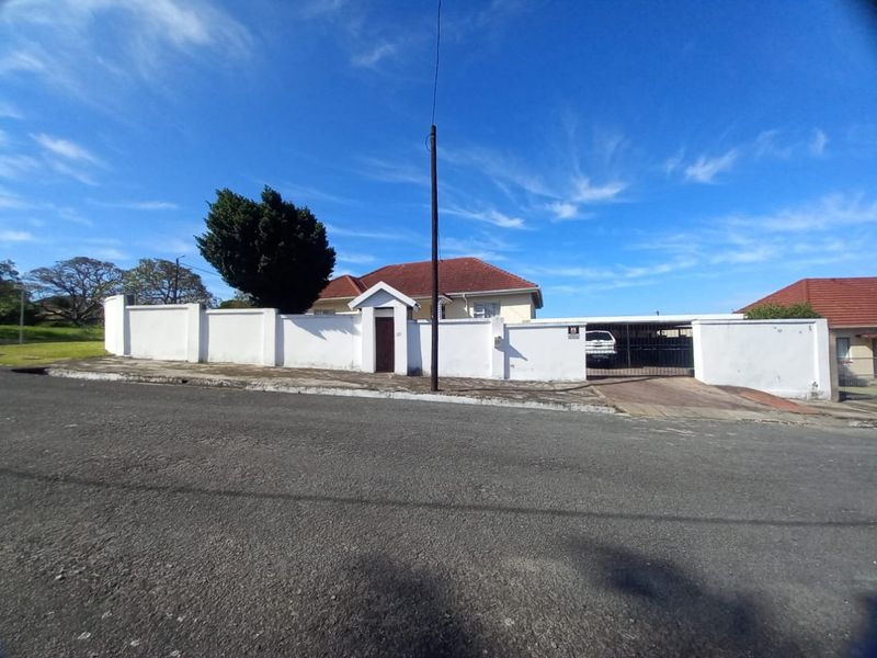 Front exterior view of the property featuring a perimeter wall, pedestrian entrance, and gated driveway access.