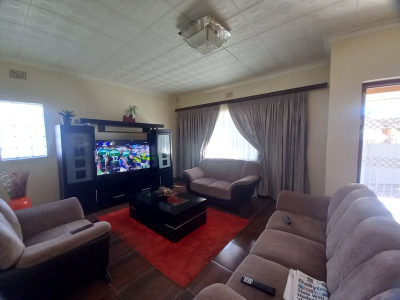 A living room featuring tiled flooring, a textured ceiling, and a glass block window, providing a functional and comfortable living space.