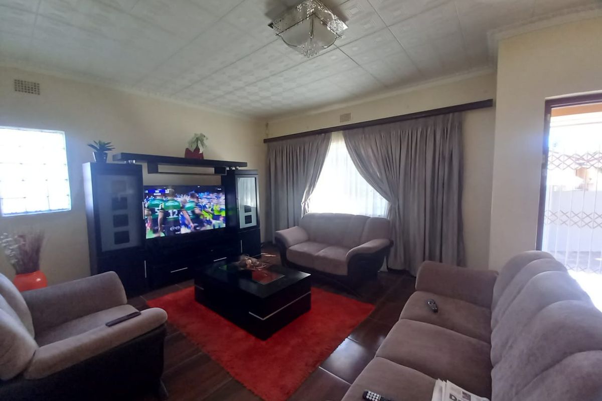 A living room featuring tiled flooring, a textured ceiling, and a glass block window, providing a functional and comfortable living space.