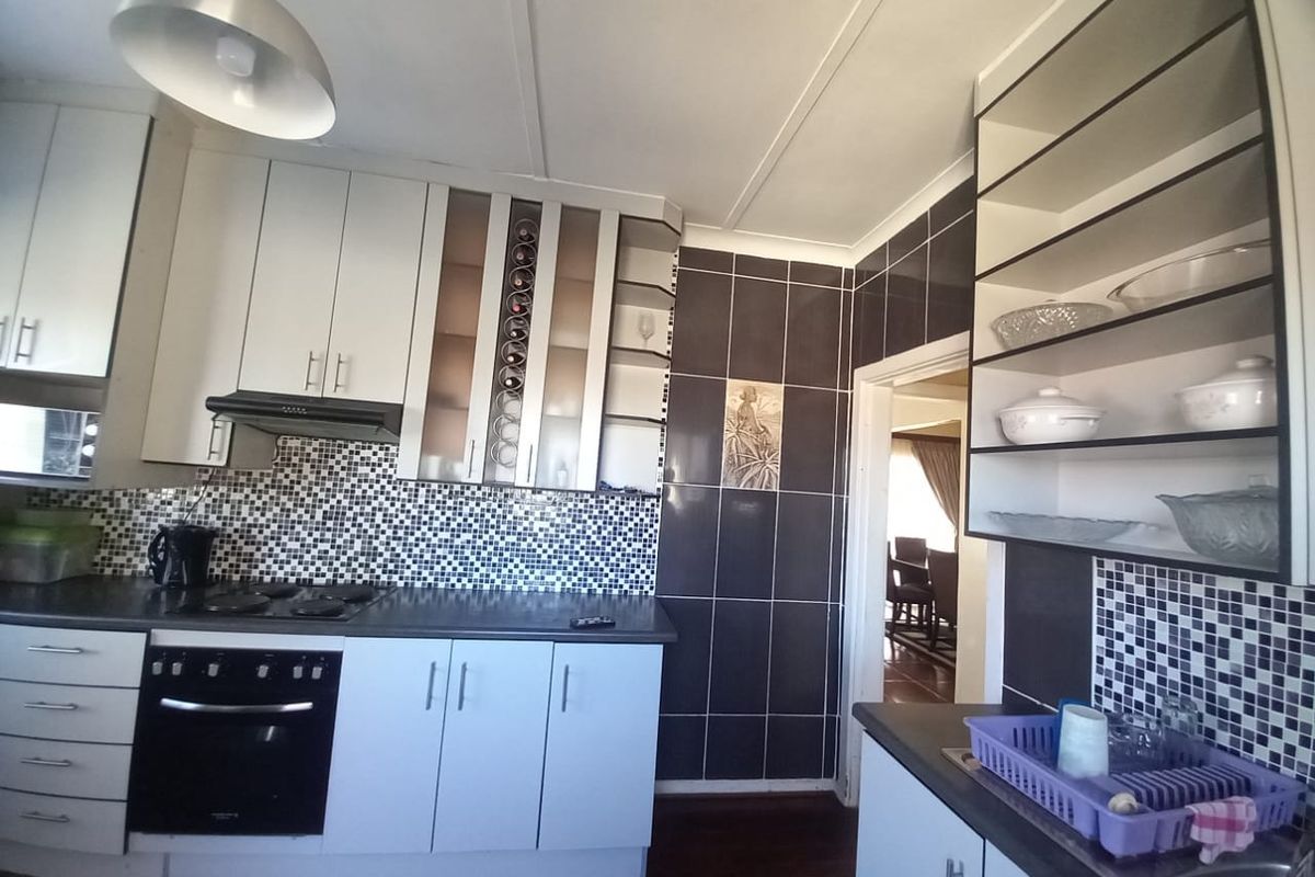 Functional kitchen featuring built-in cabinetry, mosaic tile backsplash, integrated oven, electric hob, and ample storage space with a connected dining area.