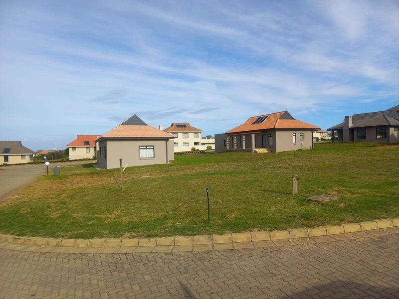 A view of residential properties in a well-maintained estate, featuring modern homes with tiled roofs, solar panels, and landscaped lawns.