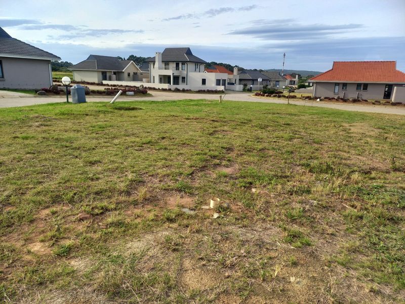 A vacant residential plot of land situated in a developed estate, featuring established surrounding homes and street access.