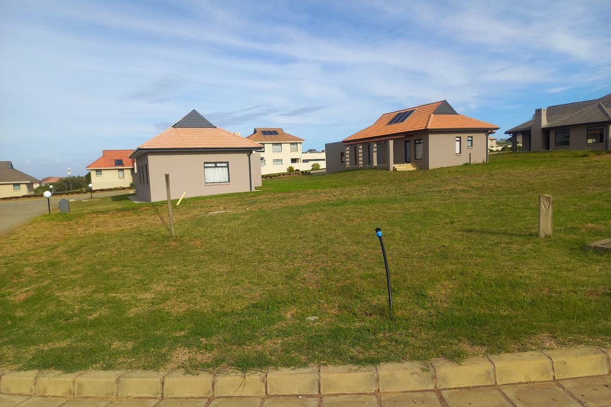 A view of a residential street featuring modern homes with tiled roofs and solar panels set on a well-maintained grassy plot.