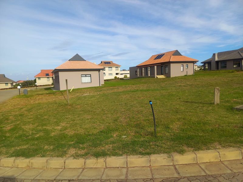 A view of a residential street featuring modern homes with tiled roofs and solar panels set on a well-maintained grassy plot.