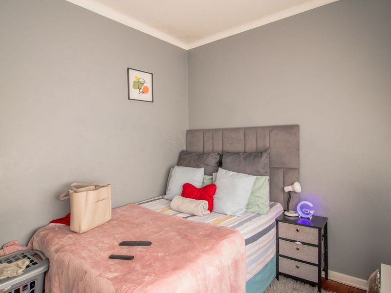 A compact bedroom featuring neutral grey walls, a fitted door, and standard skirting boards, offering a functional space for rest.