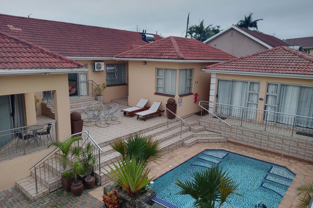 Rear exterior view featuring a multi-level tiled patio, swimming pool, and access to multiple living areas via sliding glass doors.