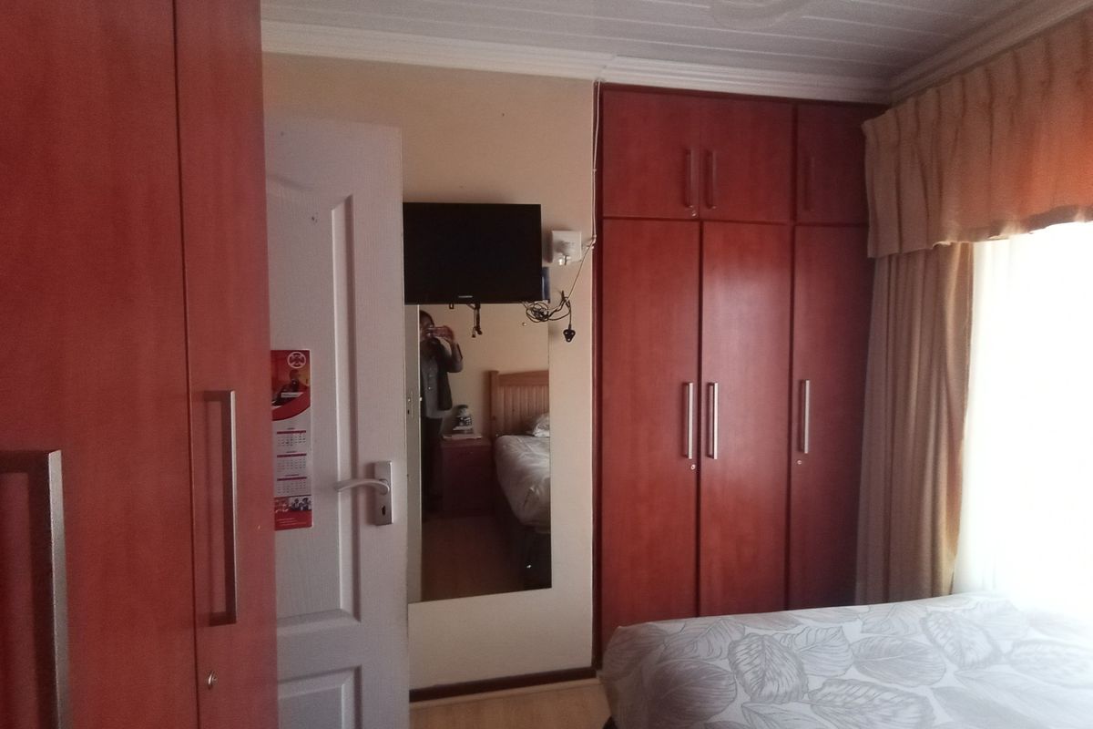 A bedroom featuring built-in wooden cupboards, laminate flooring, and a tongue and groove ceiling, providing functional storage and classic finishes.