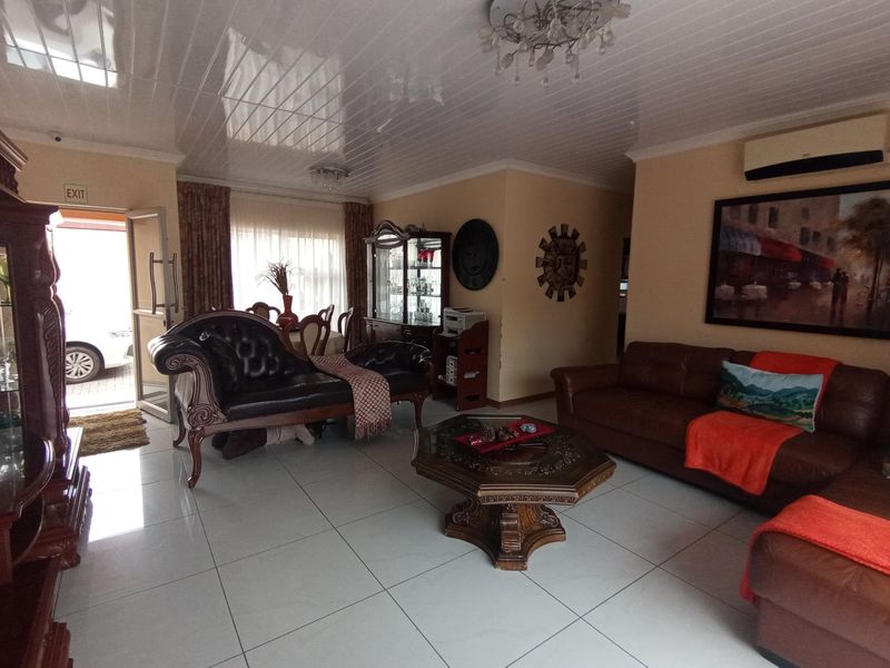 Spacious living area featuring glossy floor tiles, PVC ceiling paneling, and a wall-mounted air conditioning unit, providing a functional and well-lit living space.