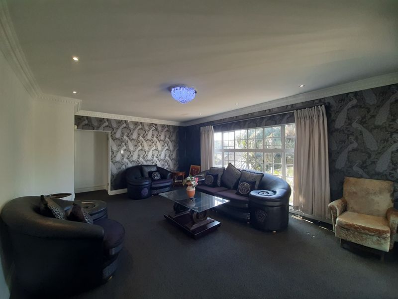 Spacious living room featuring decorative ceiling cornicing, recessed downlighting, and large windows that provide ample natural light.