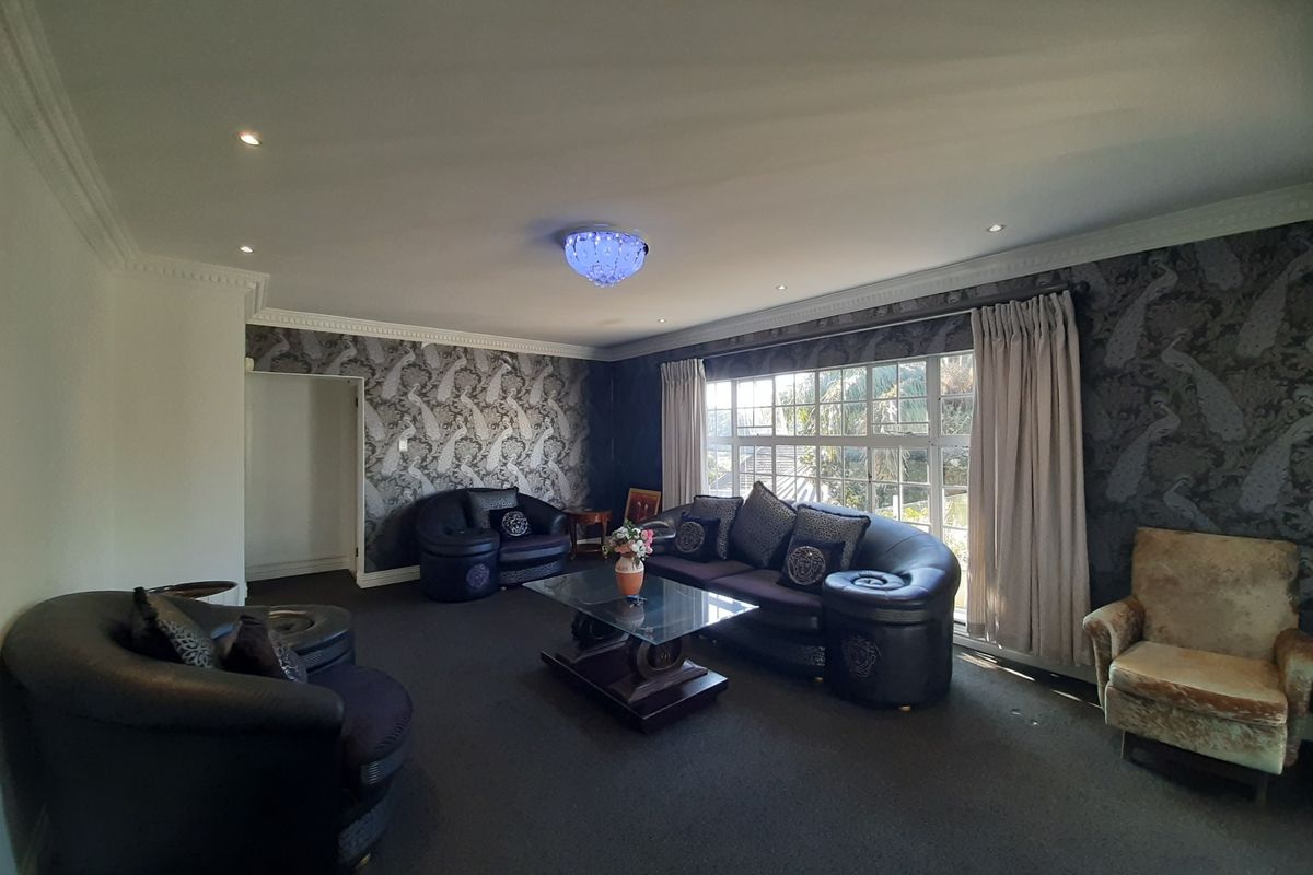 Spacious living room featuring decorative ceiling cornicing, recessed downlighting, and large windows that provide ample natural light.