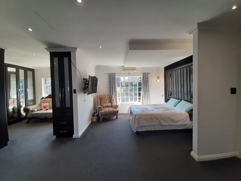 Spacious bedroom featuring built-in cupboards, recessed ceiling lighting, and a wall-mounted air conditioning unit, offering a comfortable and well-defined living space.