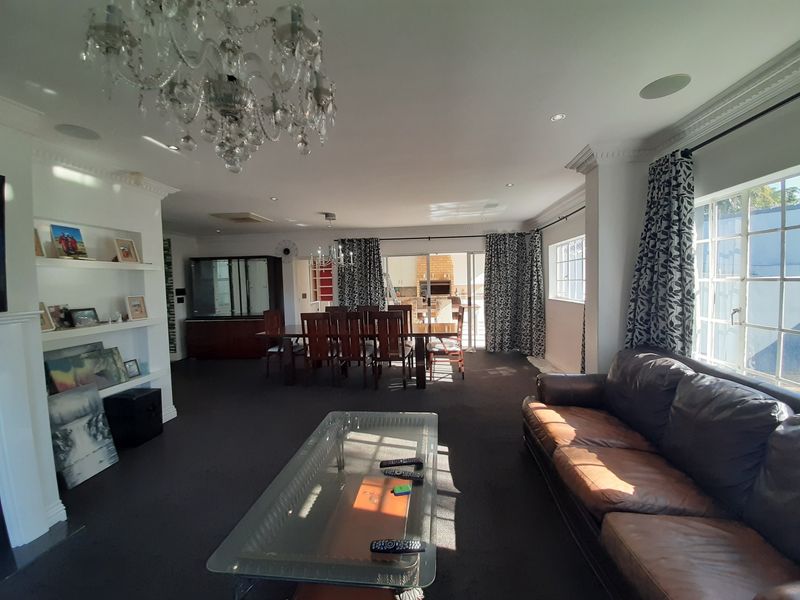 Spacious open-plan living and dining area featuring built-in shelving, crown molding, and direct access to an outdoor patio through sliding glass doors.