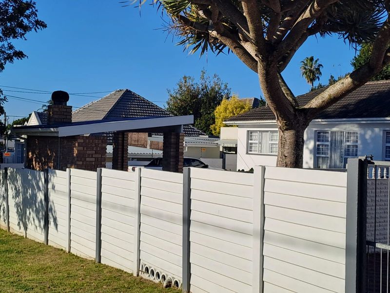Front view of the property featuring a white precast concrete boundary wall, brick chimney, and tiled roof structure.