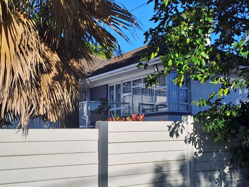 A view of the front facade of the house featuring a tiled roof, security-barred windows, and a solid precast concrete boundary wall.