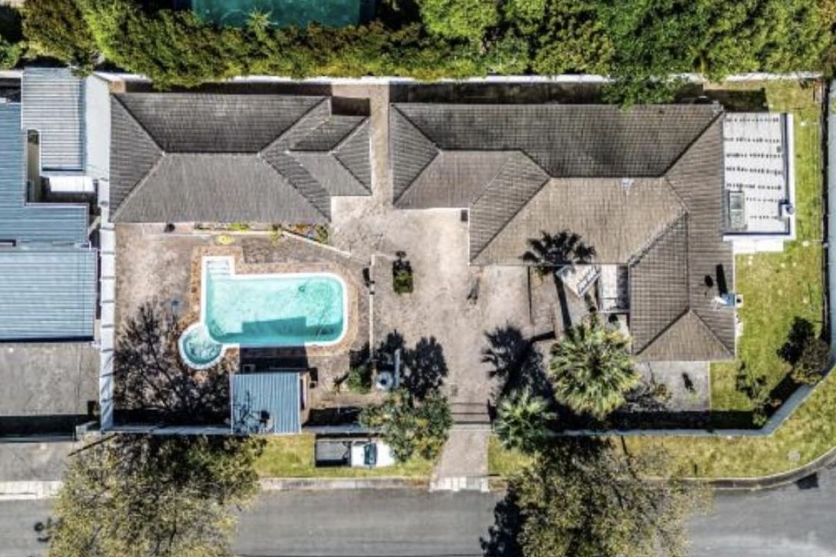 Aerial view of the property showing the house layout, tiled roof, swimming pool, and surrounding garden area.