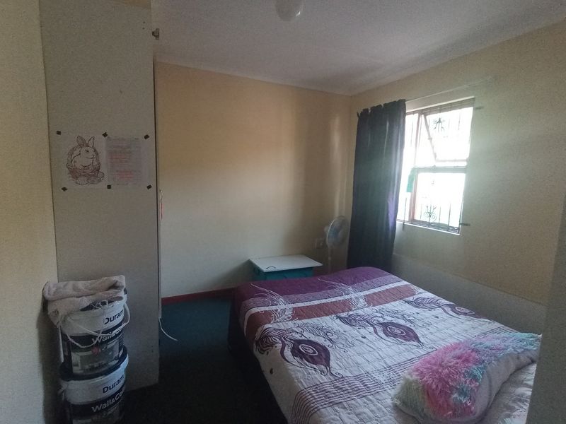 A compact bedroom featuring a built-in wardrobe and a window with security bars, requiring cosmetic updates to improve its overall appeal.