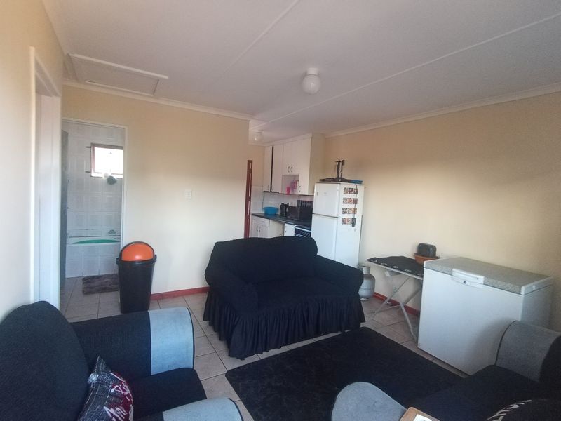 Open plan living area featuring tiled flooring and a compact kitchen corner, with direct access to an adjacent bathroom.