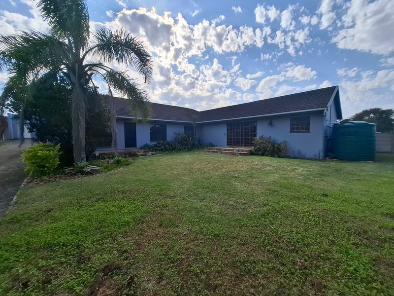 Rear view of the house featuring a spacious lawn, tiled roof, and an integrated water storage tank.