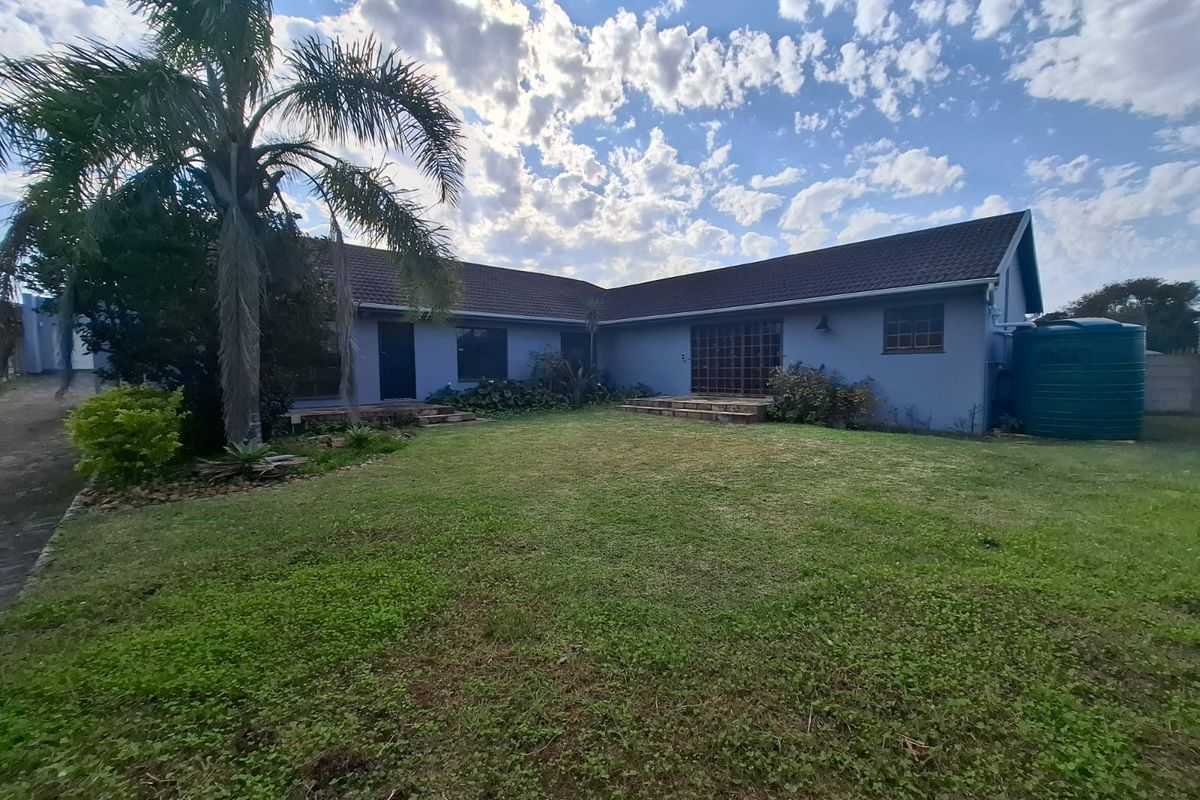 Rear view of the house featuring a spacious lawn, tiled roof, and an integrated water storage tank.