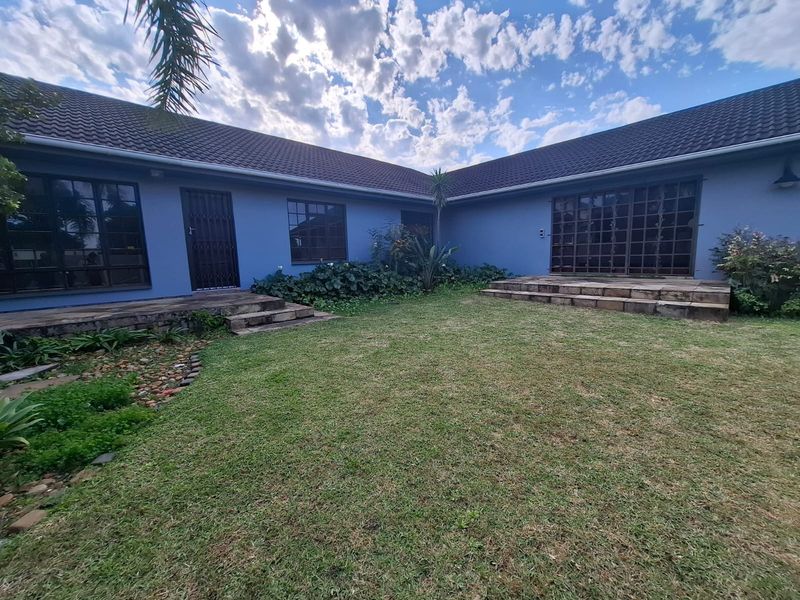 A rear view of the property featuring a landscaped garden, stone steps, and access to the interior via sliding glass doors and security gates.