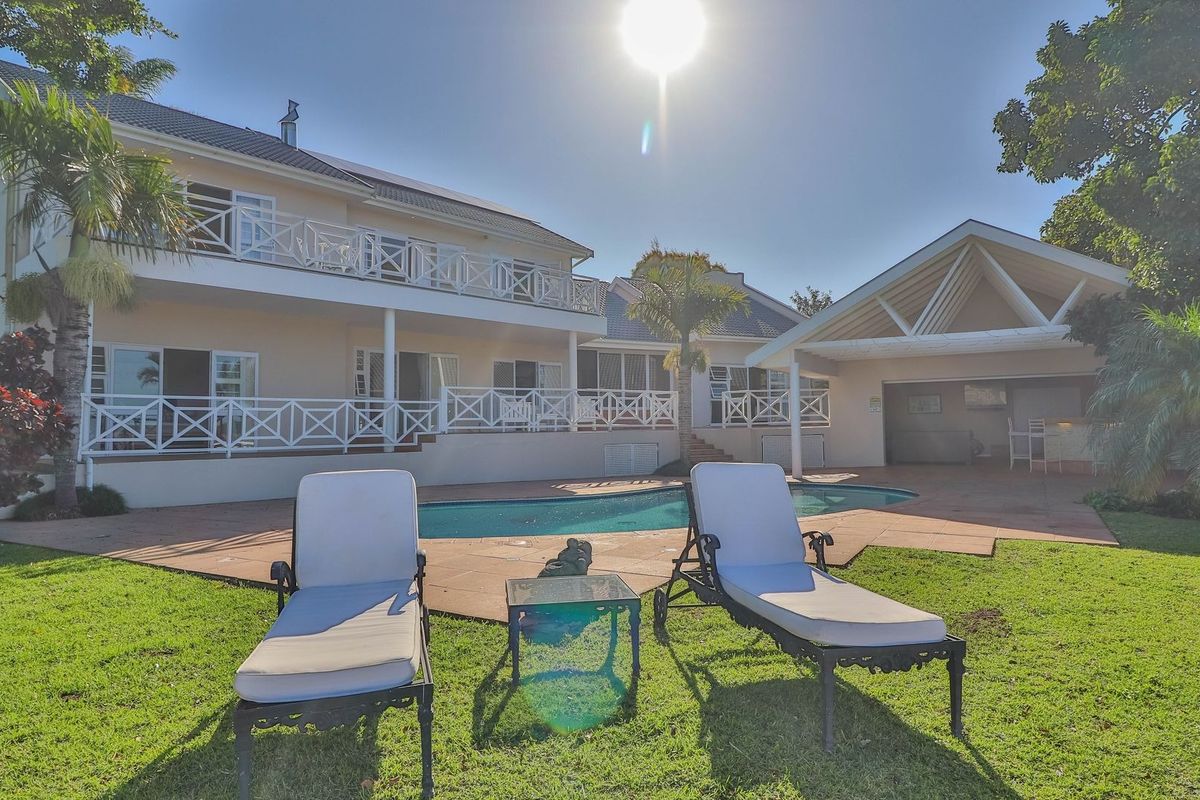 Rear view of the property featuring a swimming pool, tiled patio area, and a two-story building with balcony access.